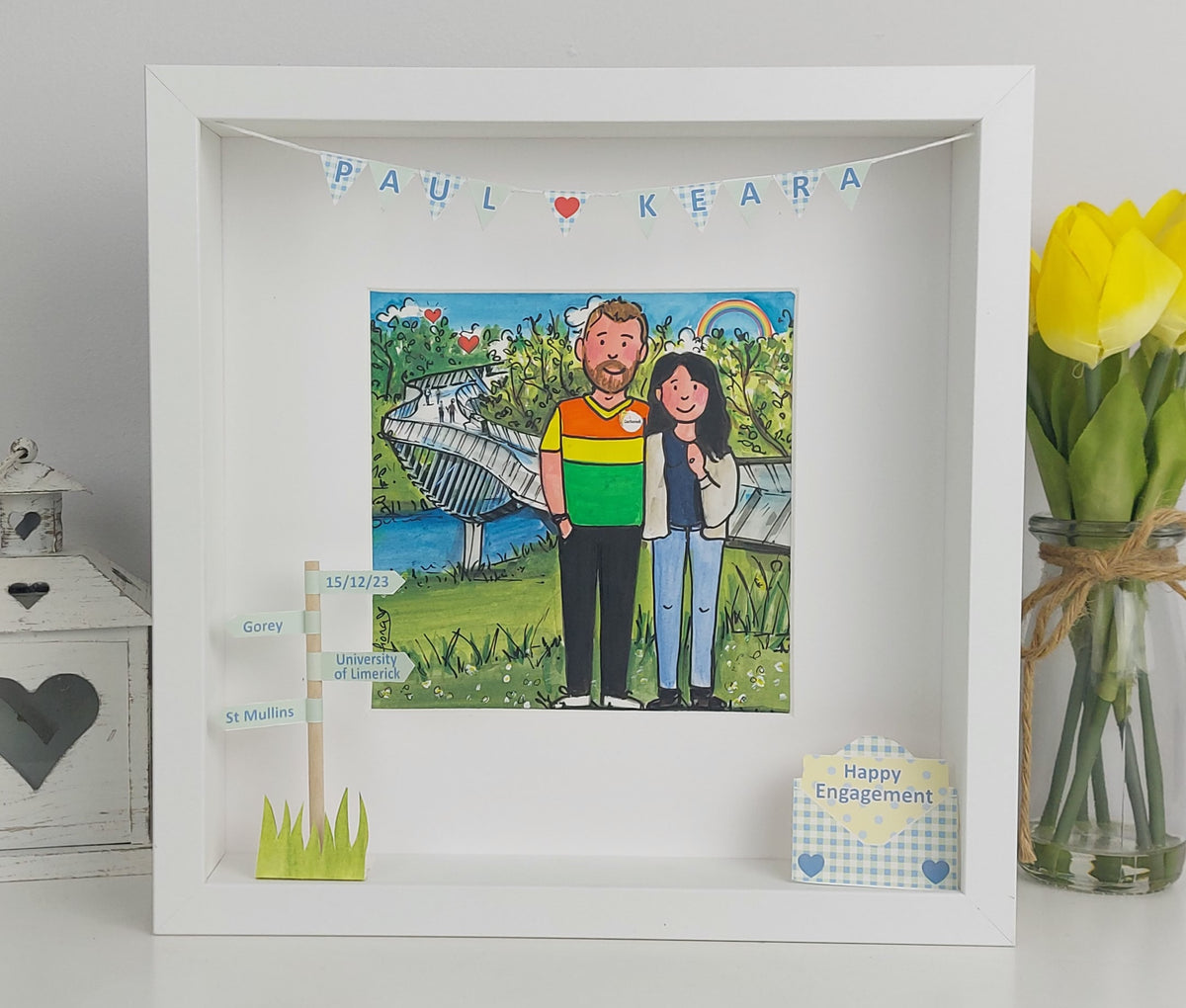 Framed artwork of a couple holding hands with a park background, featuring 'Happy Engagement' text.