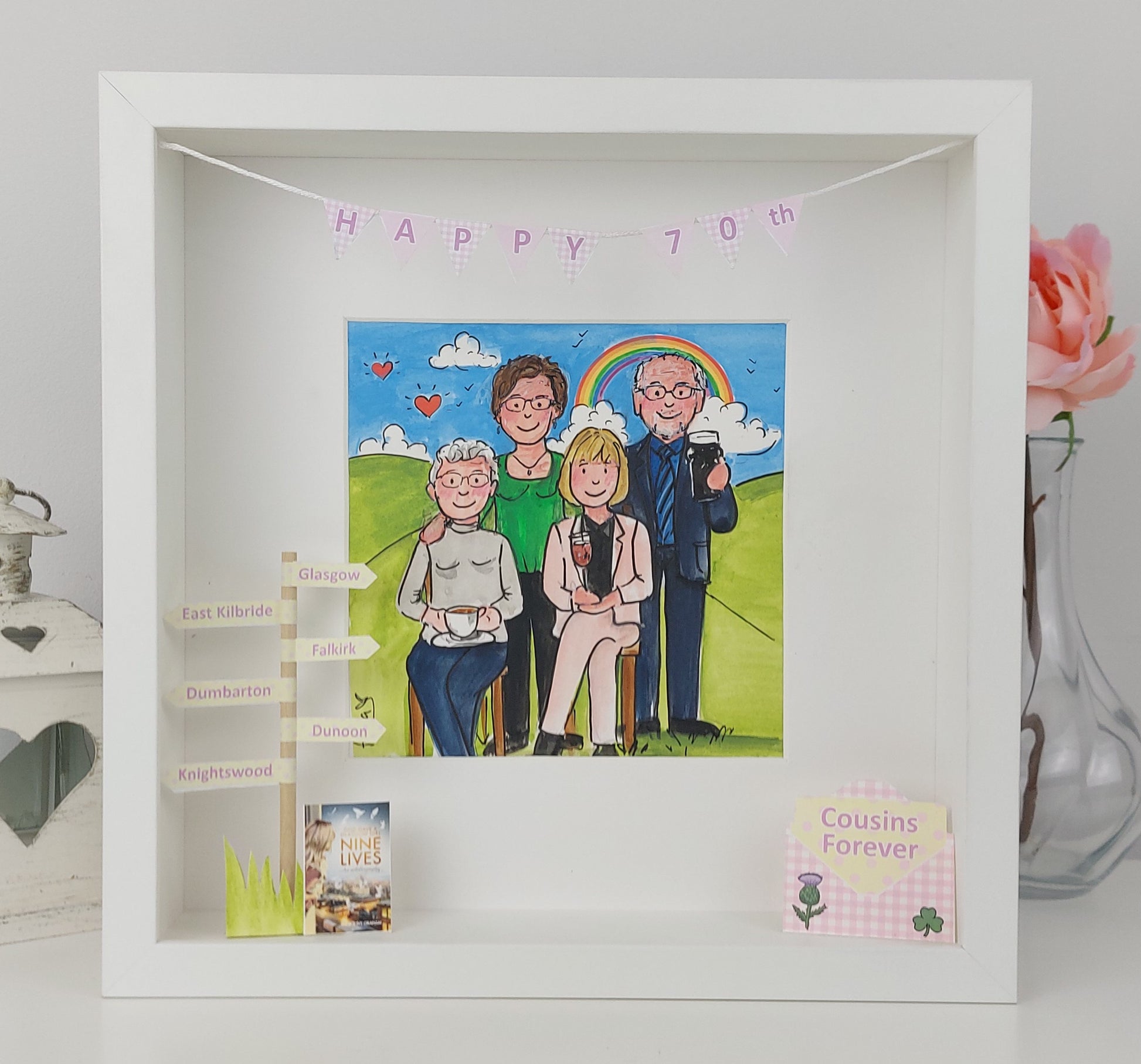 Framed artwork of a family auntie and cousins 'Happy 70th' banner, displayed on a white surface.