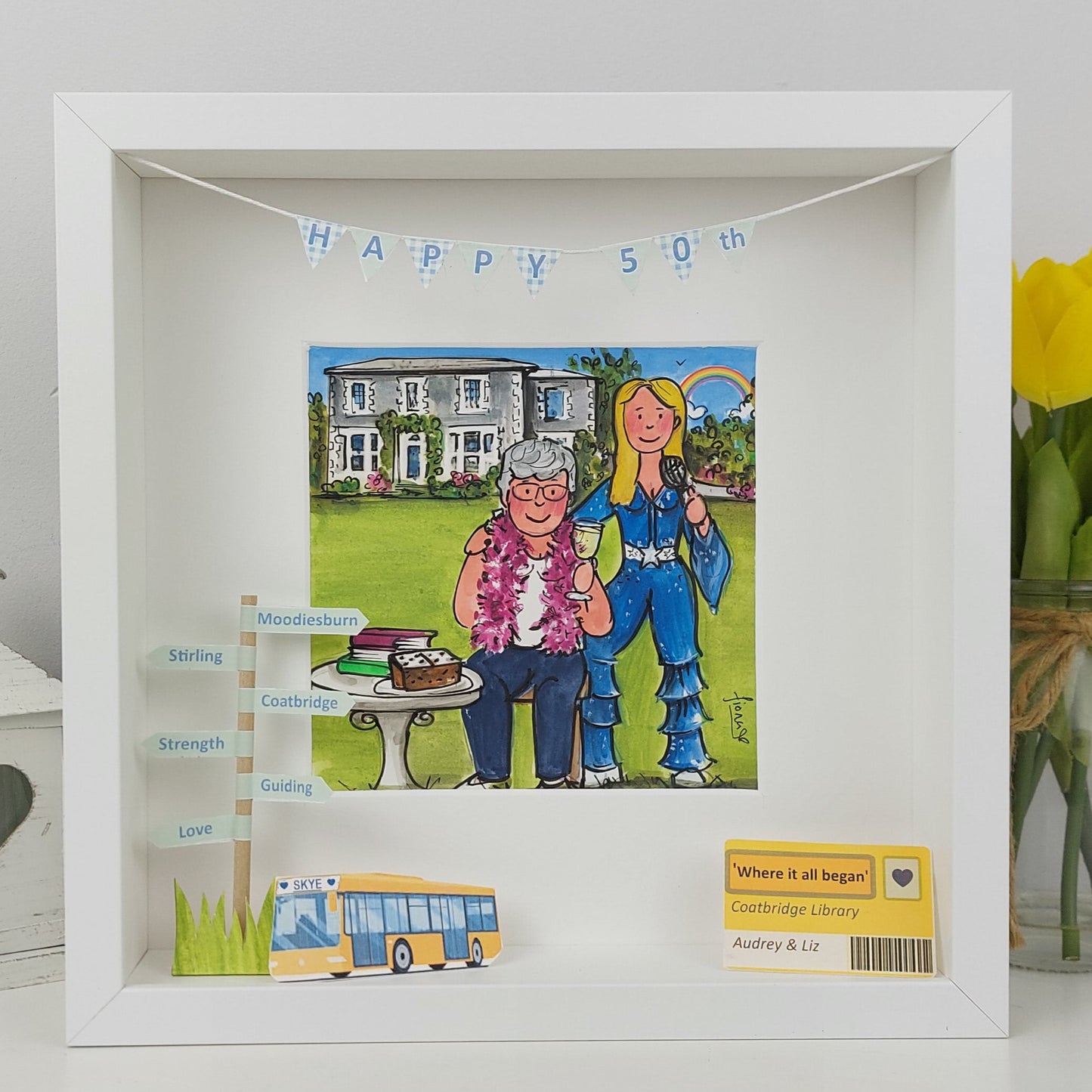 Framed artwork celebrating a 50th anniversary with a couple, house, and bus illustration.