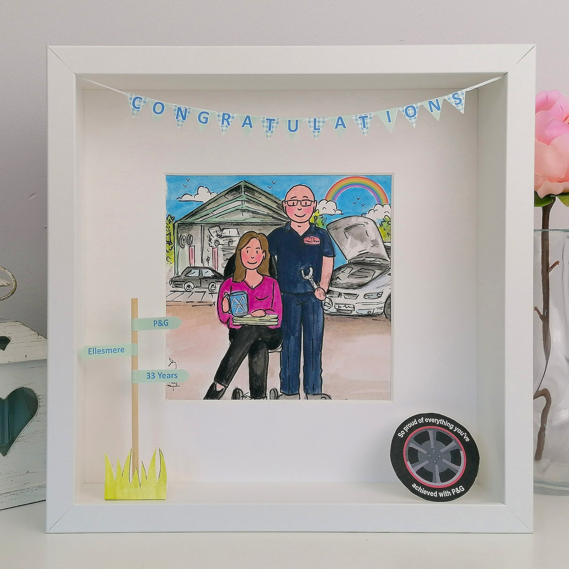 Framed artwork of a couple with a car and 'Congratulations' banner, with a pink flower in the background.