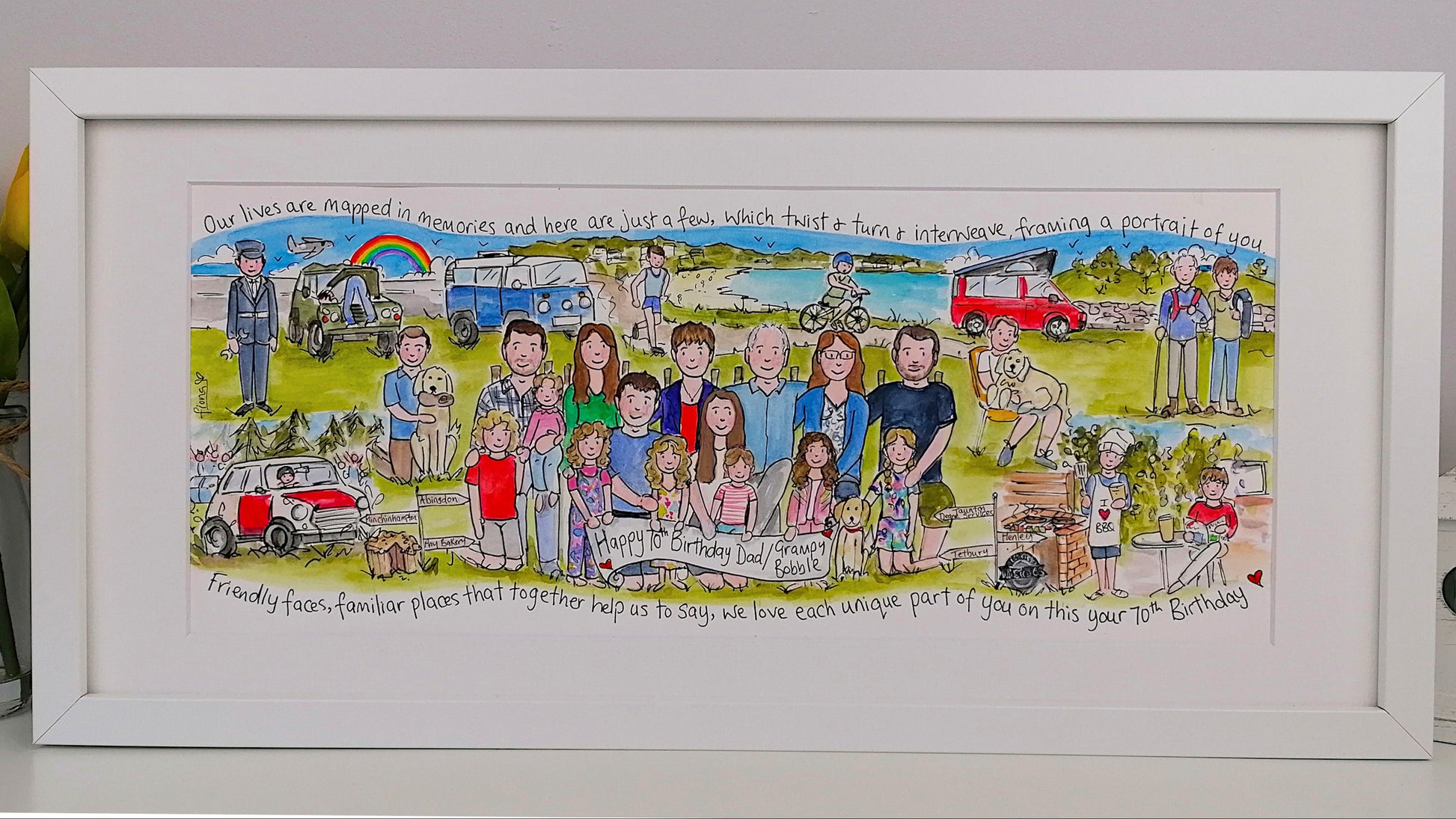 Framed artwork with a colorful illustration of people and scenes, placed on a light gray surface.