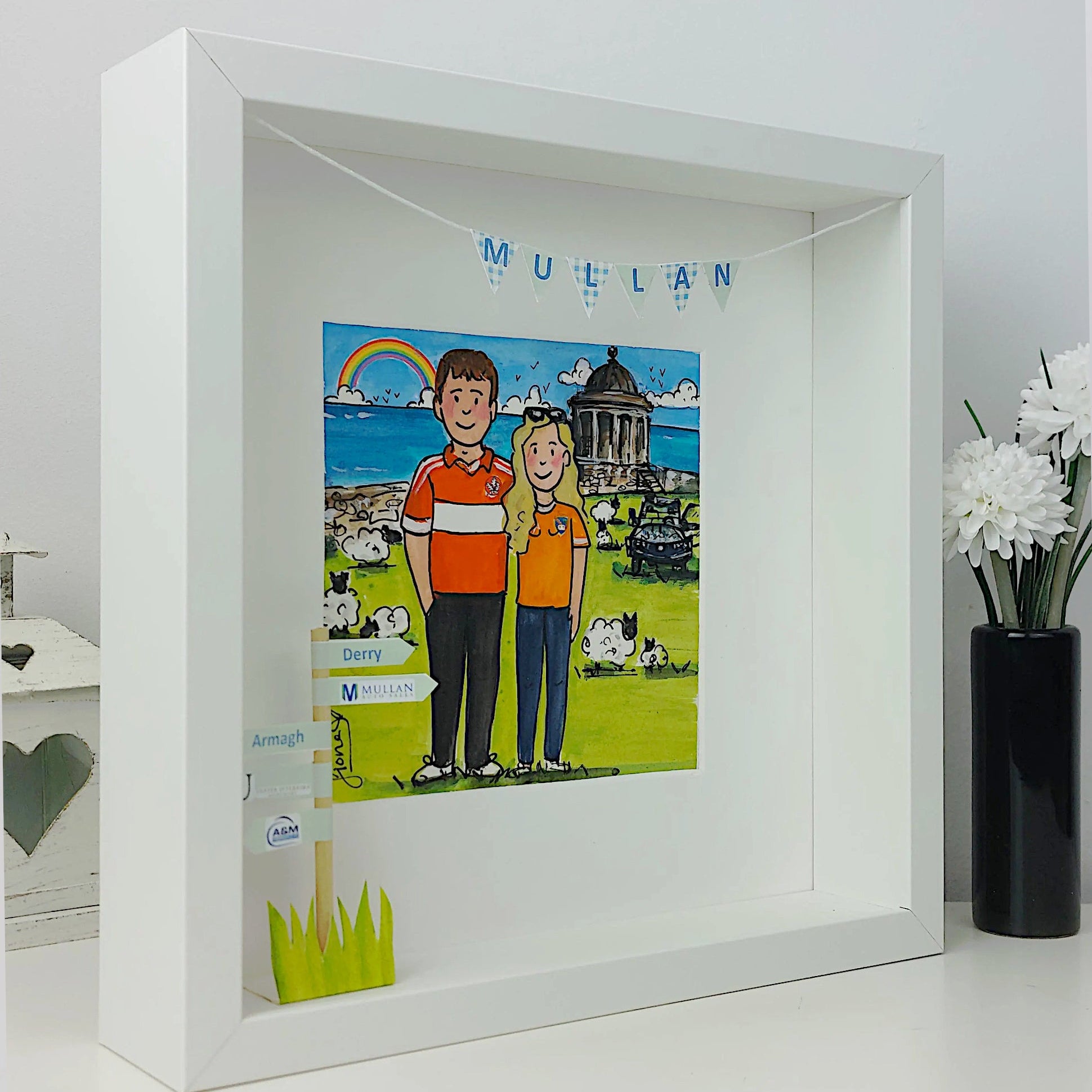 Framed artwork of engaged man and women in sports shirts with a scenic background, displayed on a white surface.