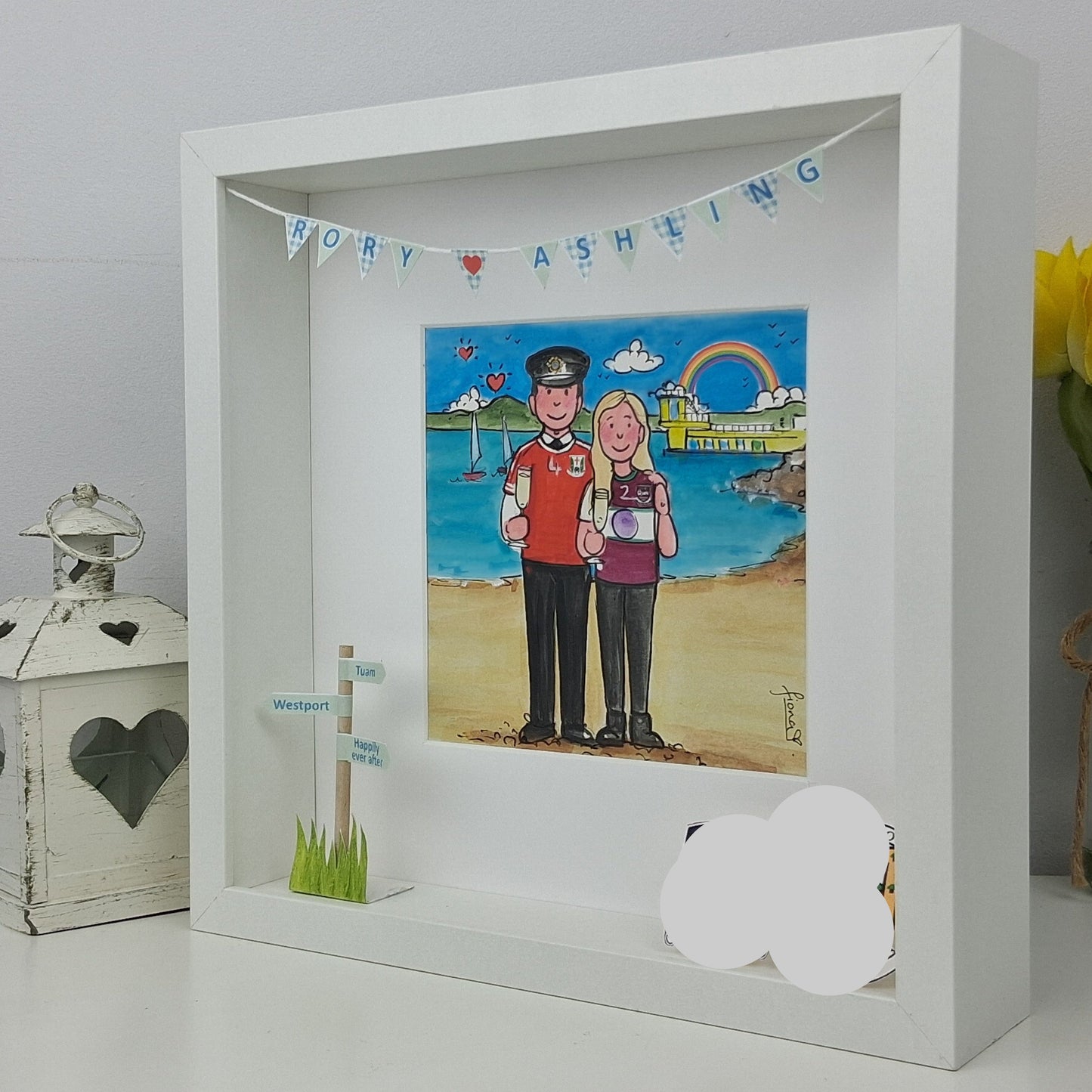 Framed artwork of a couple on a beach with decorative elements.