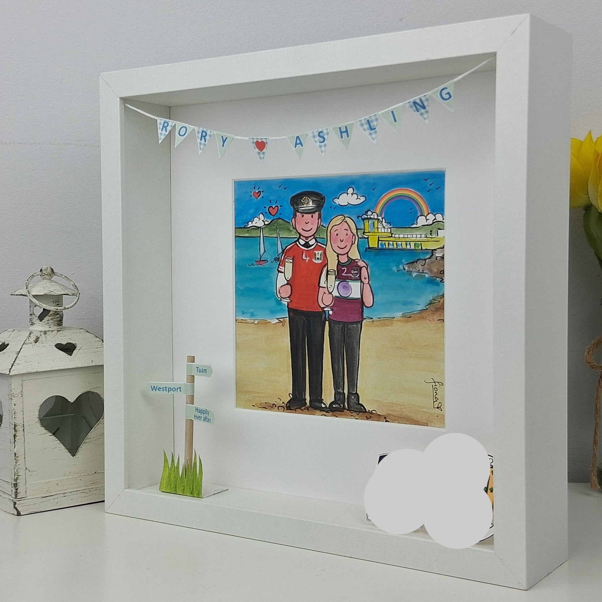 Framed artwork of a couple on a beach with decorative elements.