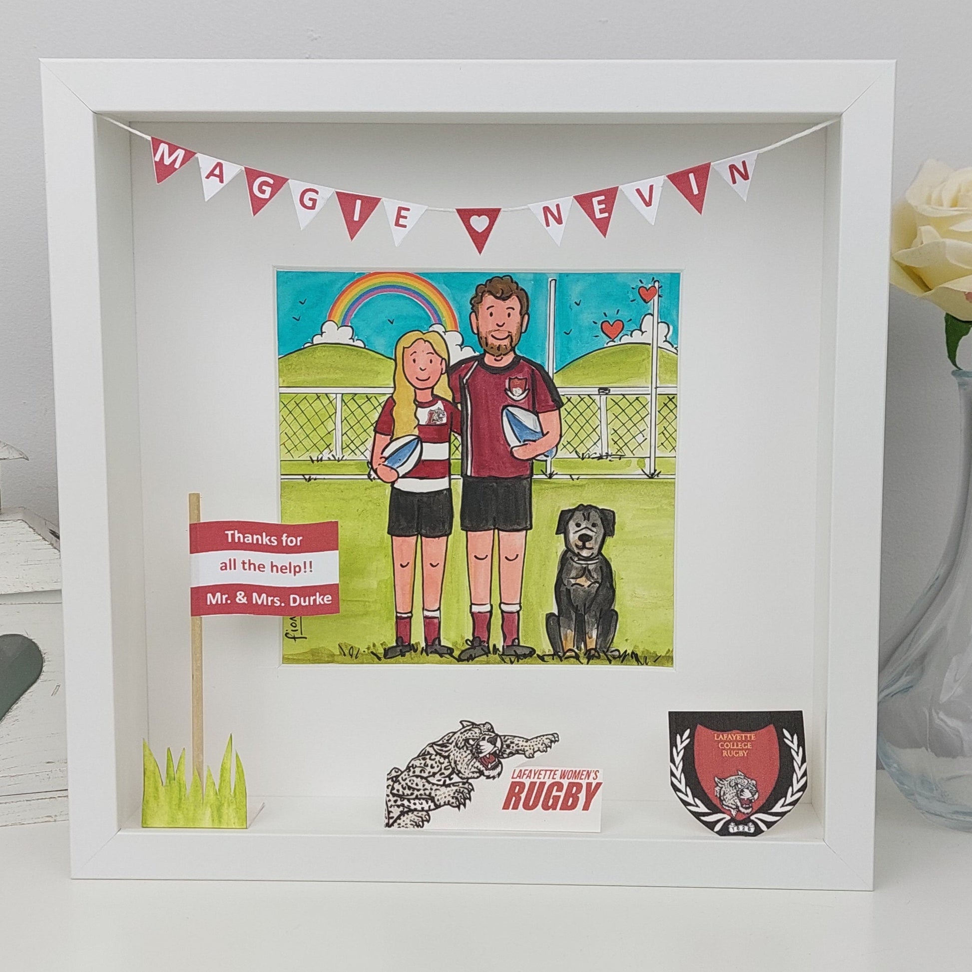 Framed artwork of a couple with a dog, surrounded by rugby-themed items.
