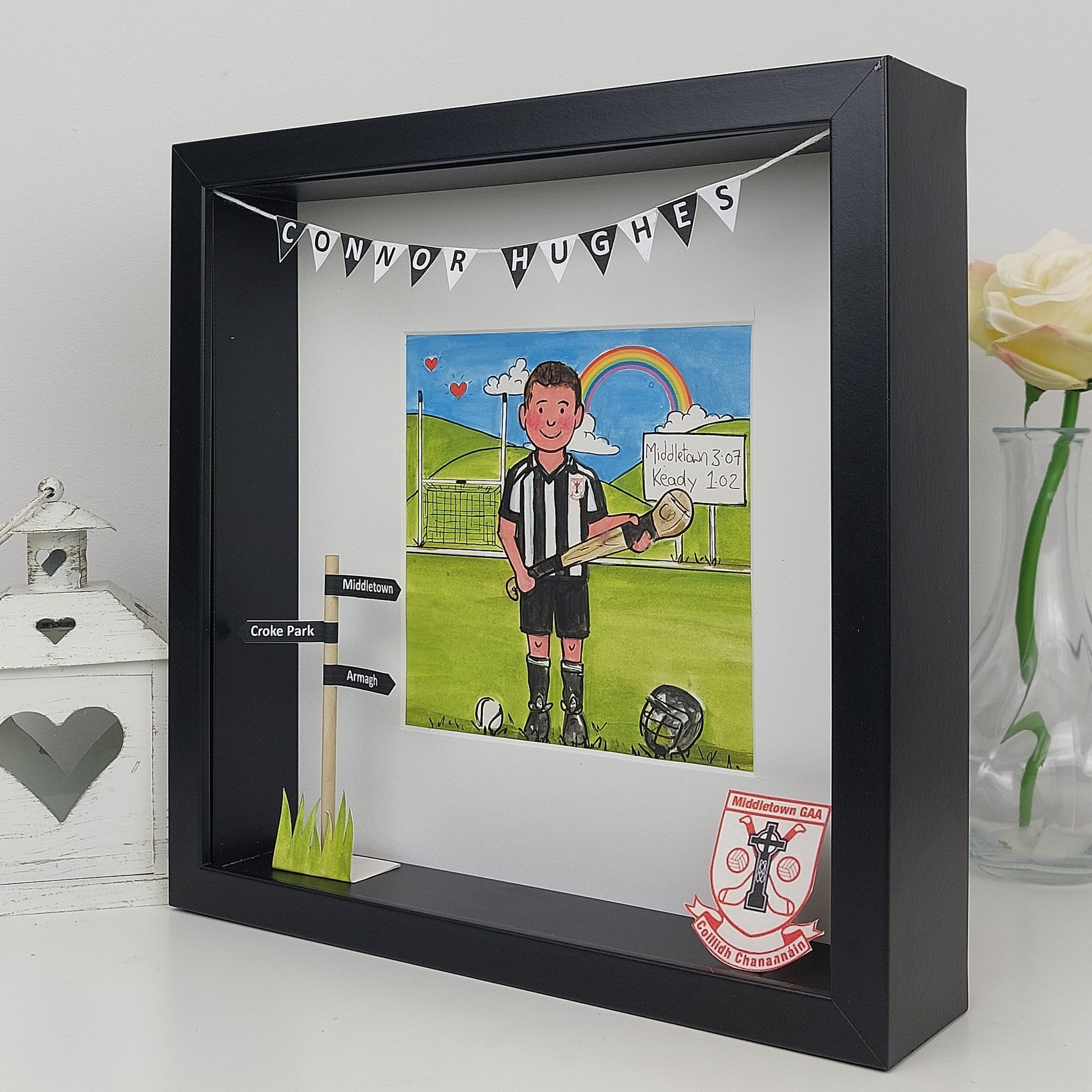 Artistic depiction of a sports player holding a hurl in a black frame with decorative elements.