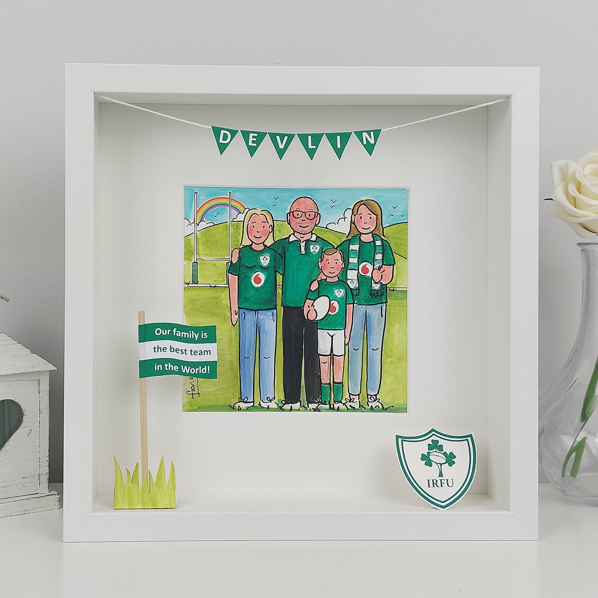 Framed artwork of a family in green shirts with text and flags, on a light gray background.