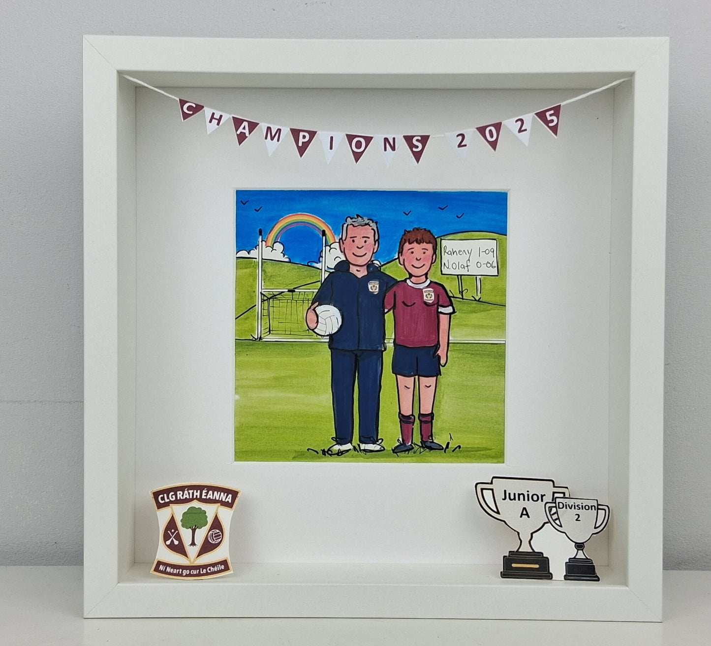 Framed artwork of two people on a soccer field with trophies and a banner.