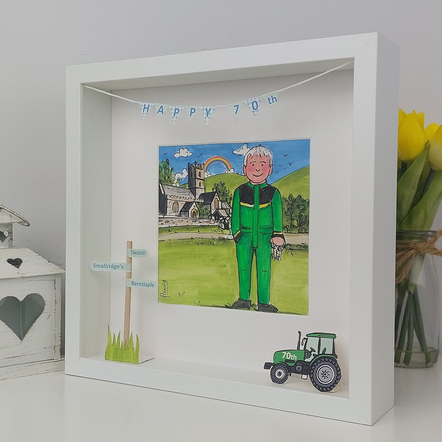 Framed artwork with a man in a green outfit, tractor, and 'Happy 70th' banner.