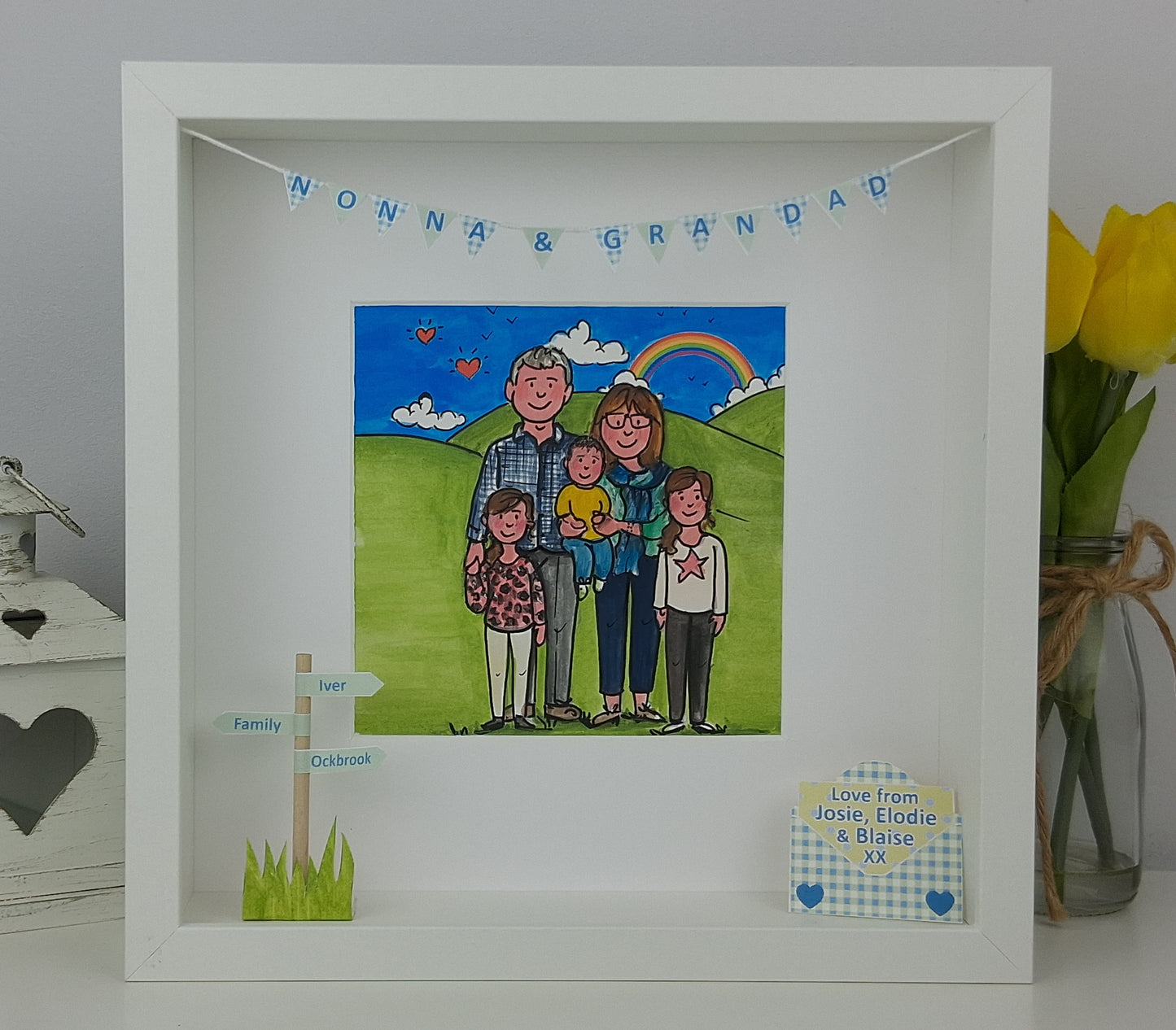 Framed illustration of a family with 'Nonna & Grandad' above, on a grassy field with a rainbow.