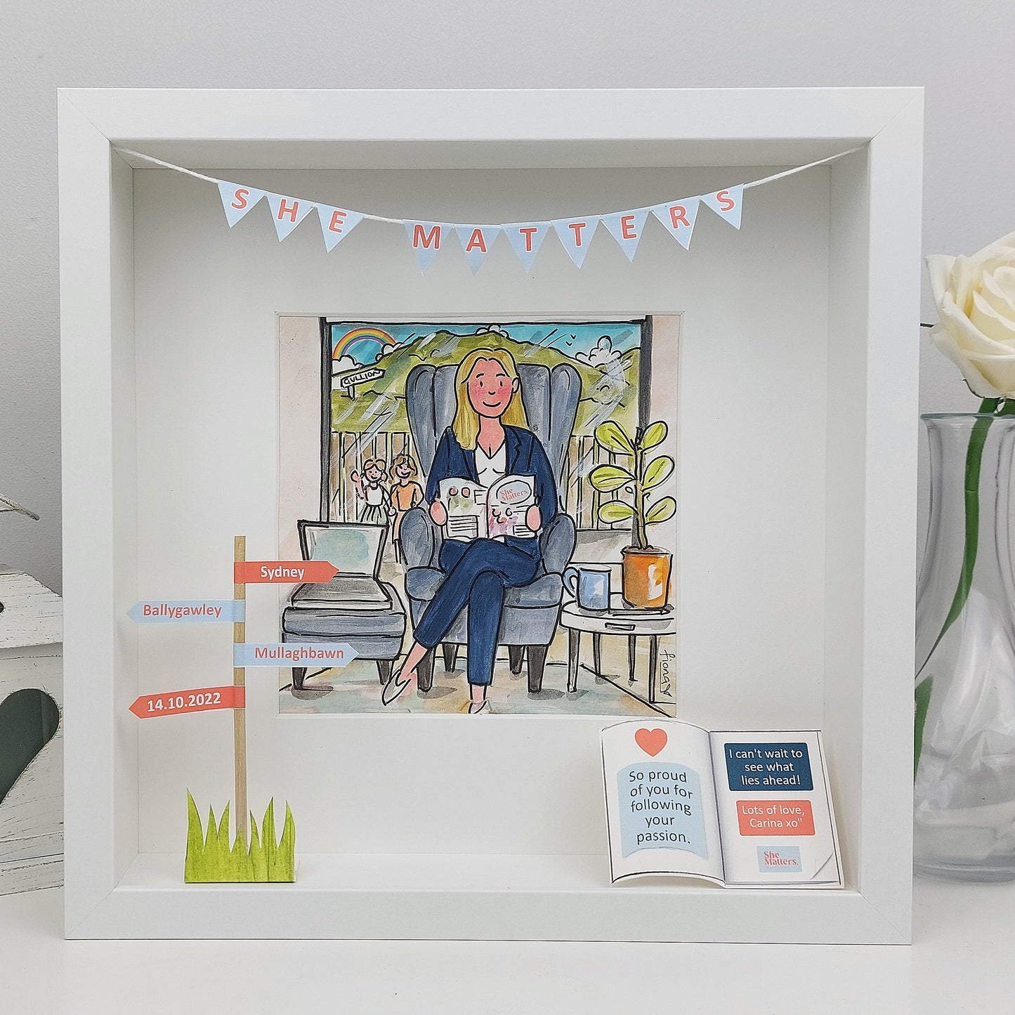 Decorative shadow box with illustrations and text on a white surface.