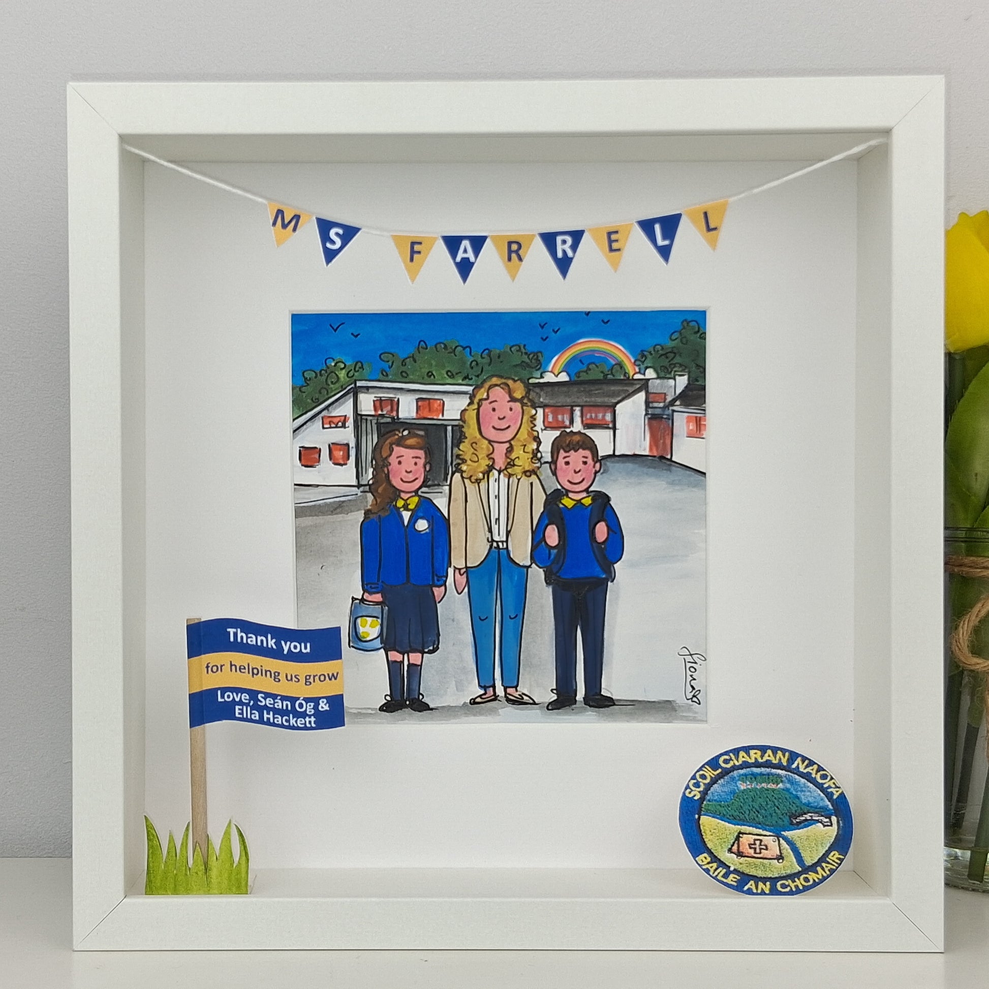 Framed artwork of three people in front of a school and crest elements.