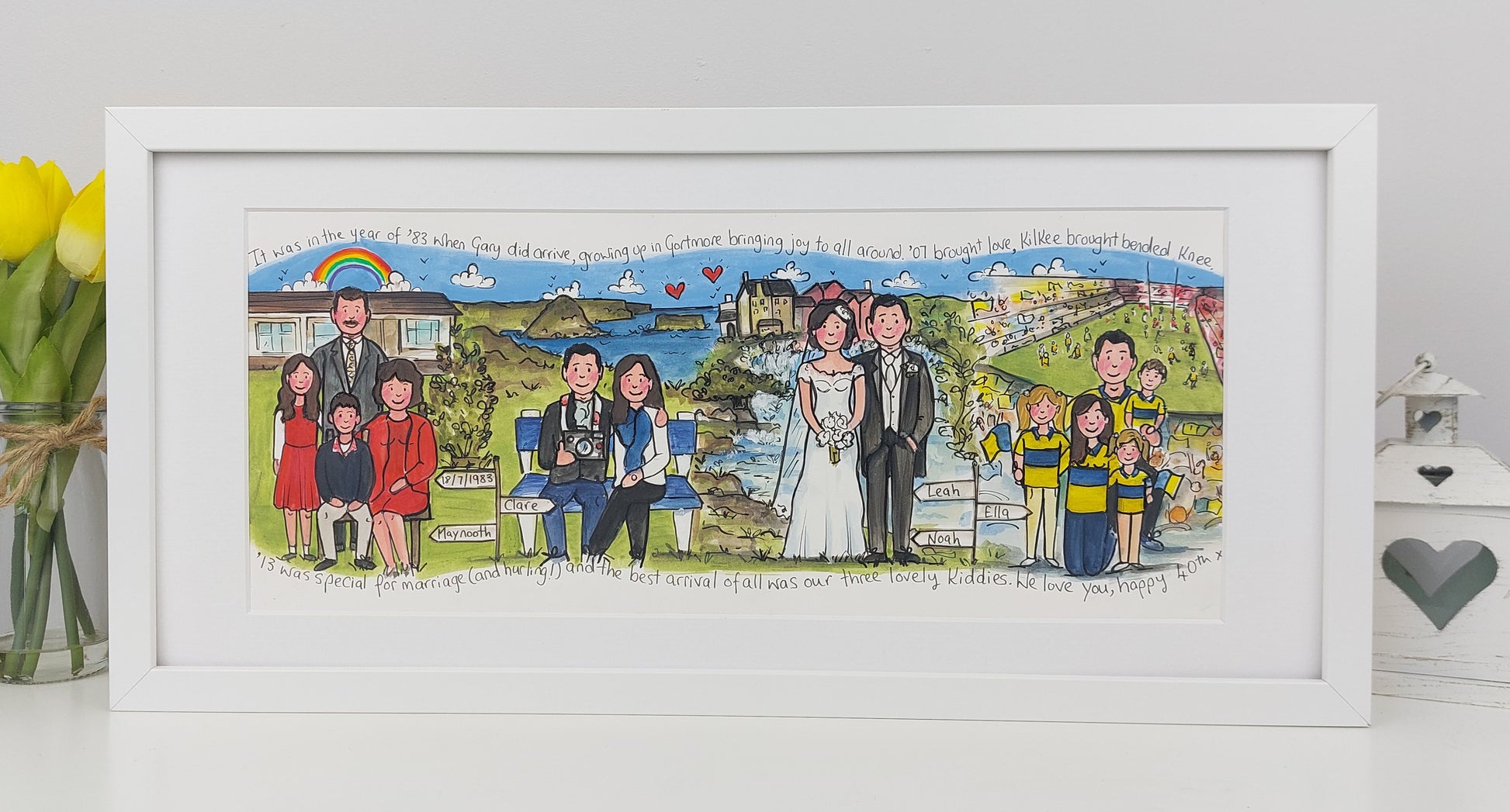 Framed artwork of a family scene with a couple and children, set against a scenic background.