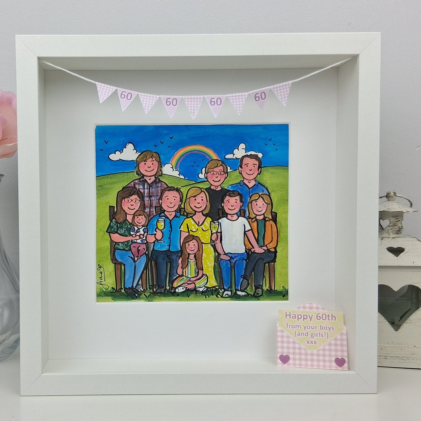 Framed artwork of a family sitting together with a rainbow and 'Happy 60th' banner. 