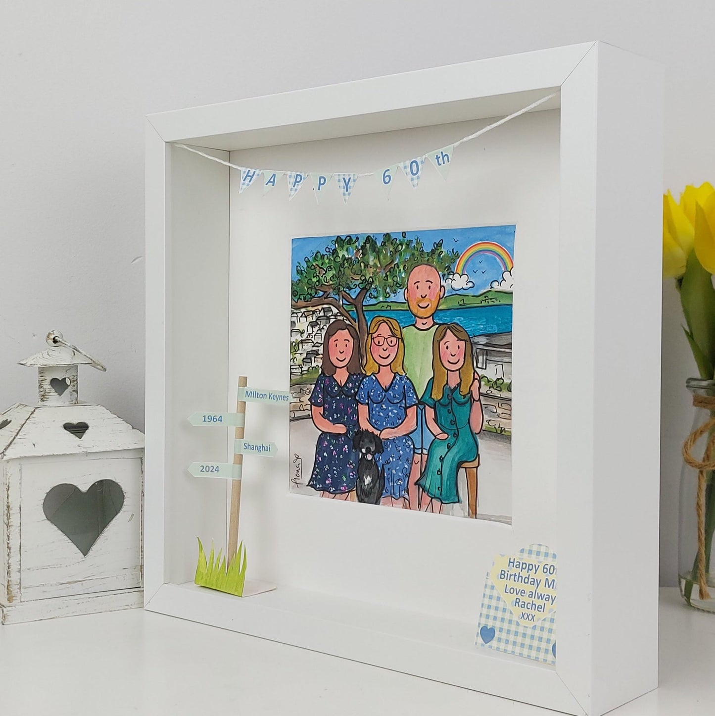 Framed artwork with a family portrait and birthday message on a white surface.