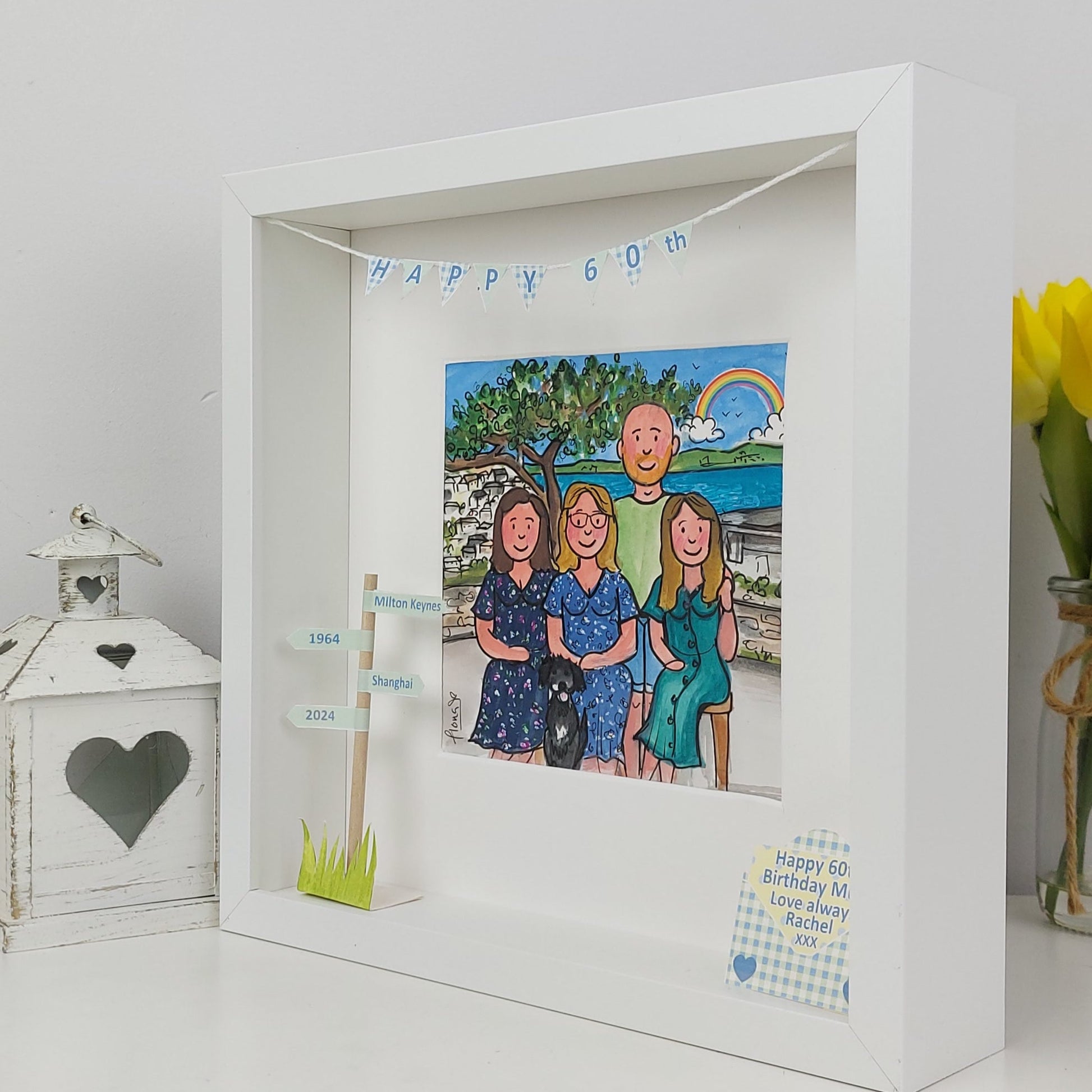 Framed artwork with a family portrait and birthday message on a white surface.
