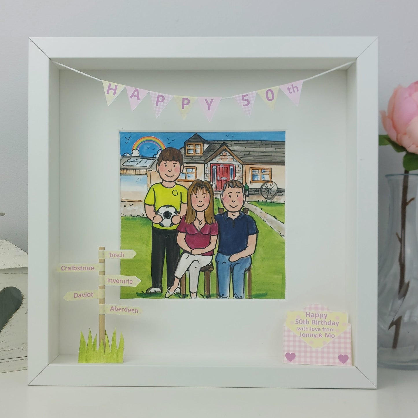 Framed artwork of a family with a 'Happy 50th' banner, Mum and son and husband