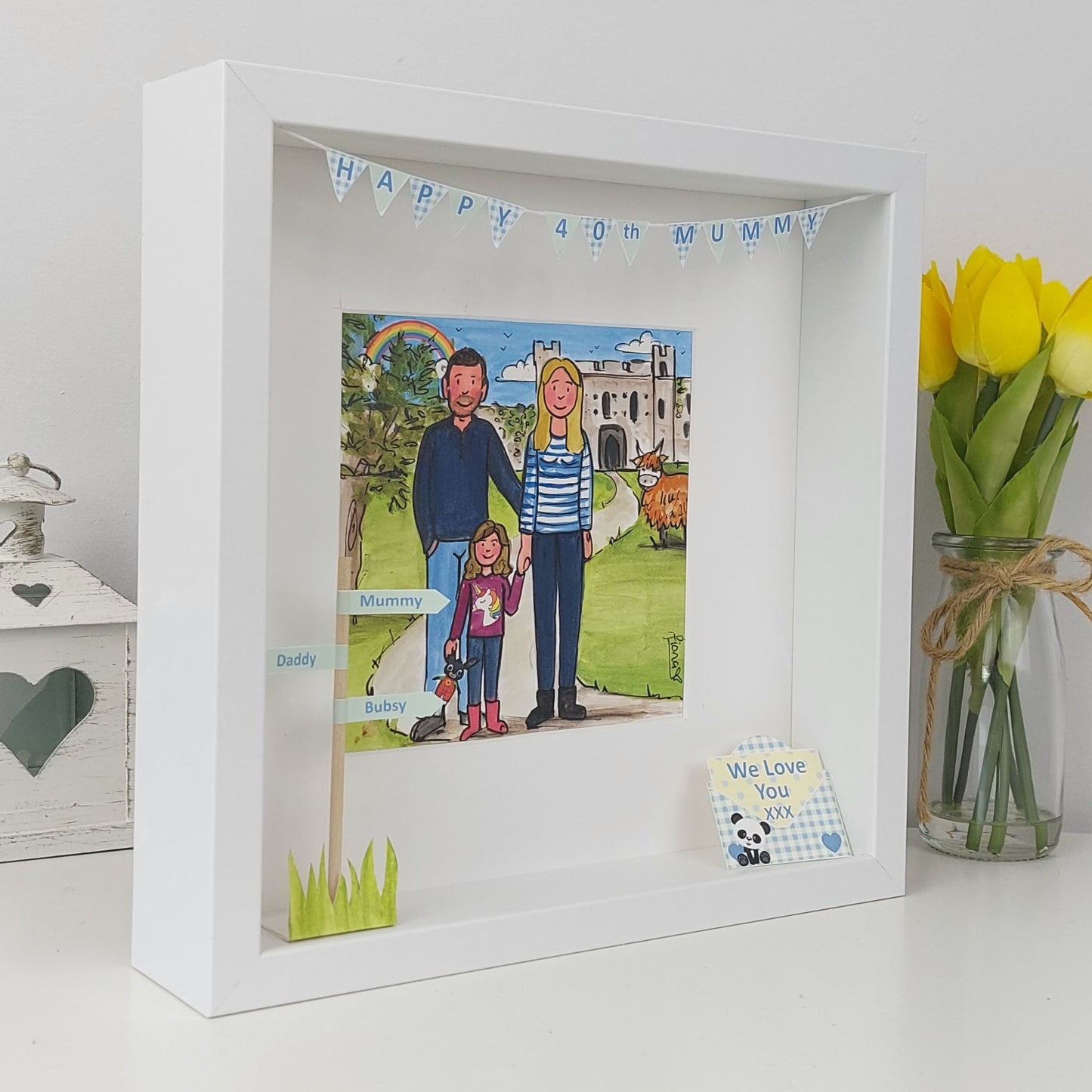 White framed artwork of a family with mumm, daddy and daughter and a castle. We love you envelope