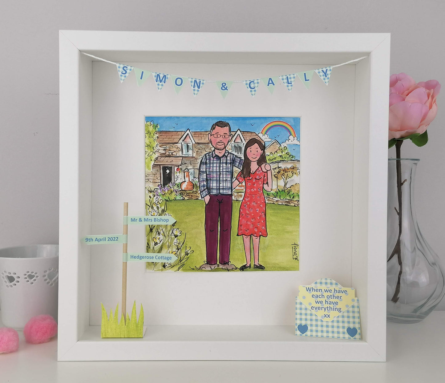 Framed artwork of a couple with a house illustration, personalized with names and date.