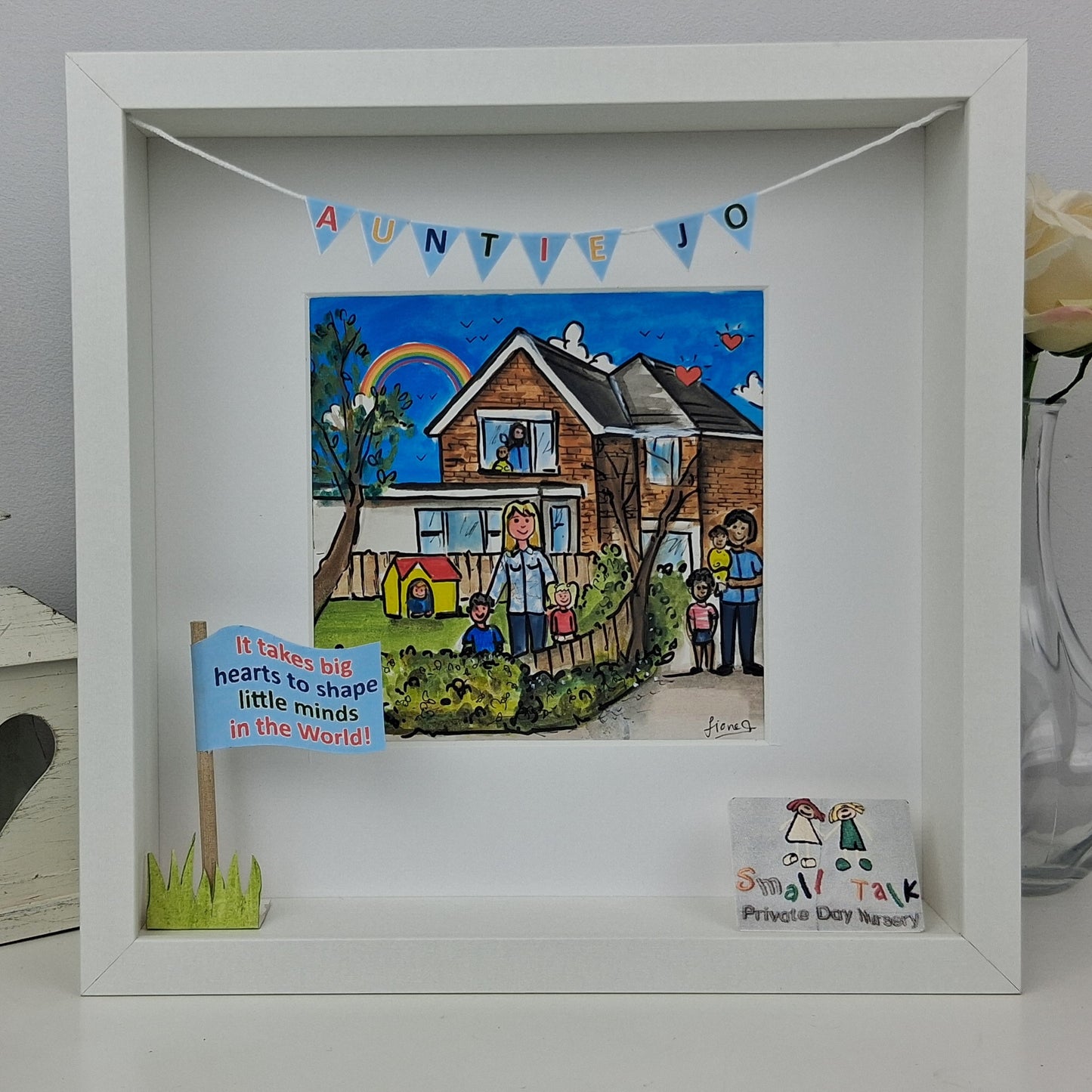 Framed artwork with a house illustration and text, placed on a surface.