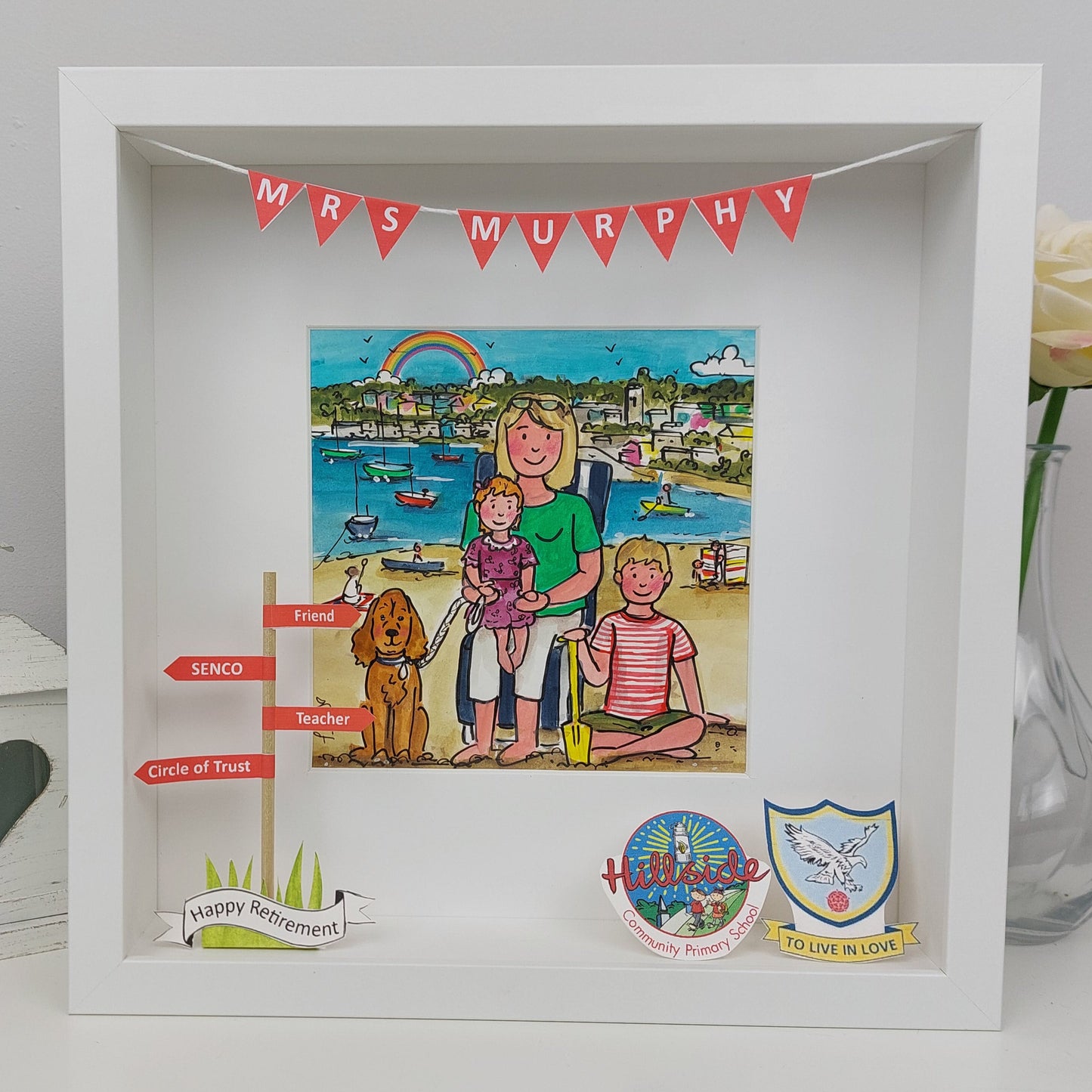Decorative shadow box with a family scene and various elements on a white surface.