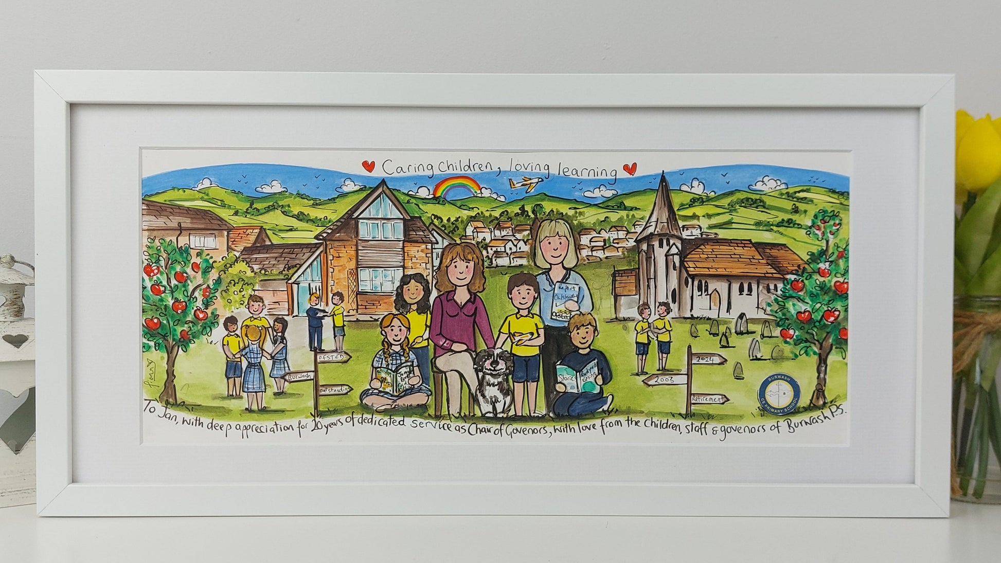 Framed artwork of a family and children in a village scene with a white frame.