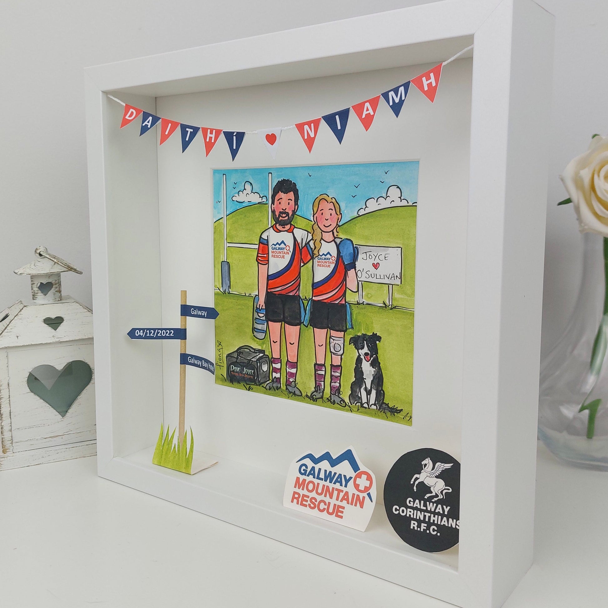 Framed artwork of two people with a dog, featuring sports team logos and a small flag.