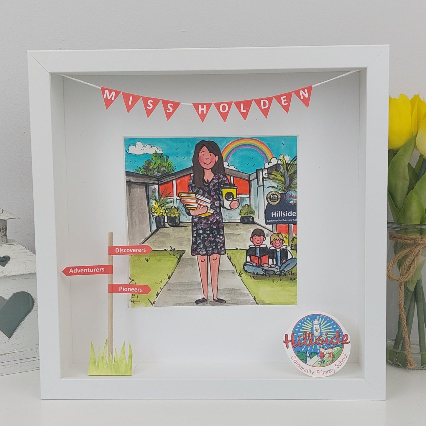 Framed artwork of a teacher with a school setting illustration, featuring 'Miss Holden' at the top.