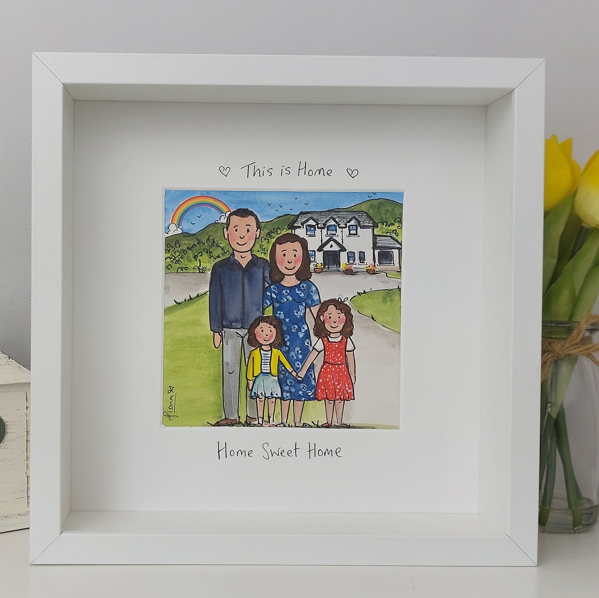 Framed illustration of a family with a house and rainbow, labeled 'This is Home'.