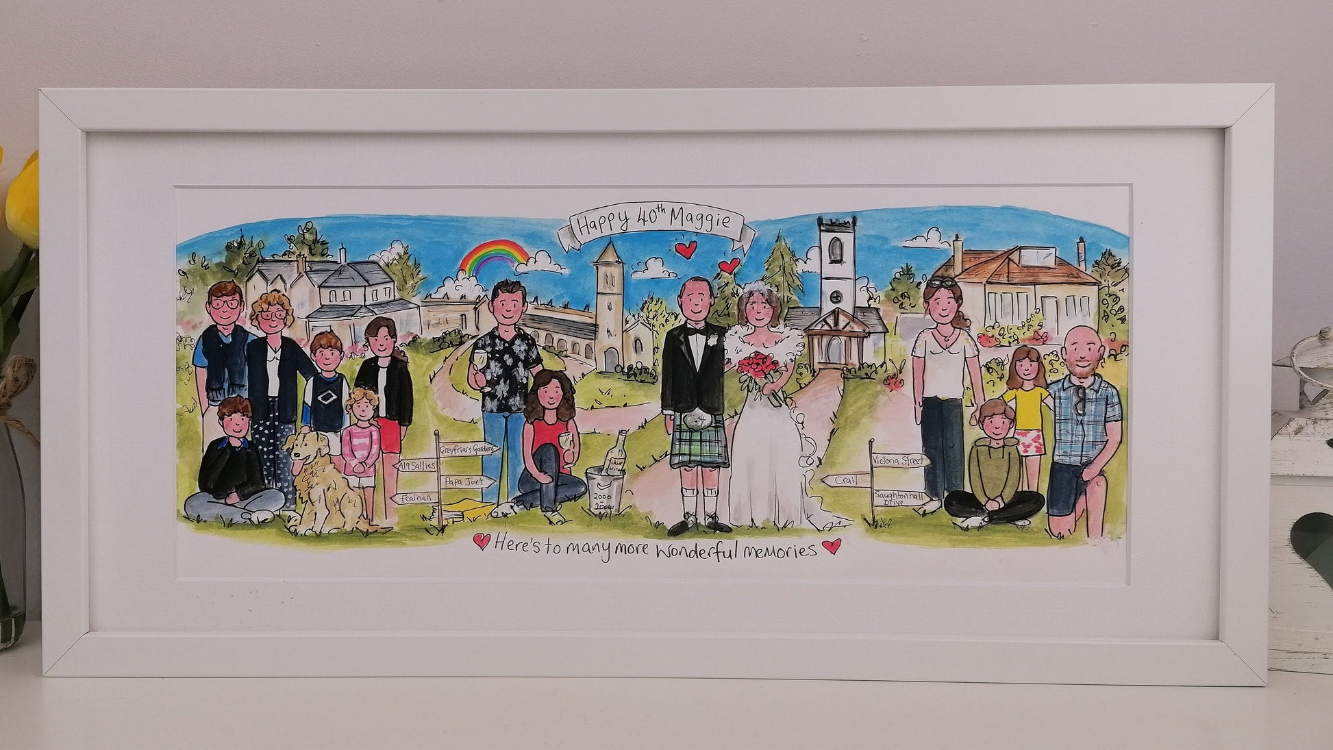 Framed artwork of a family scene with a church and rainbow, featuring people in various poses.