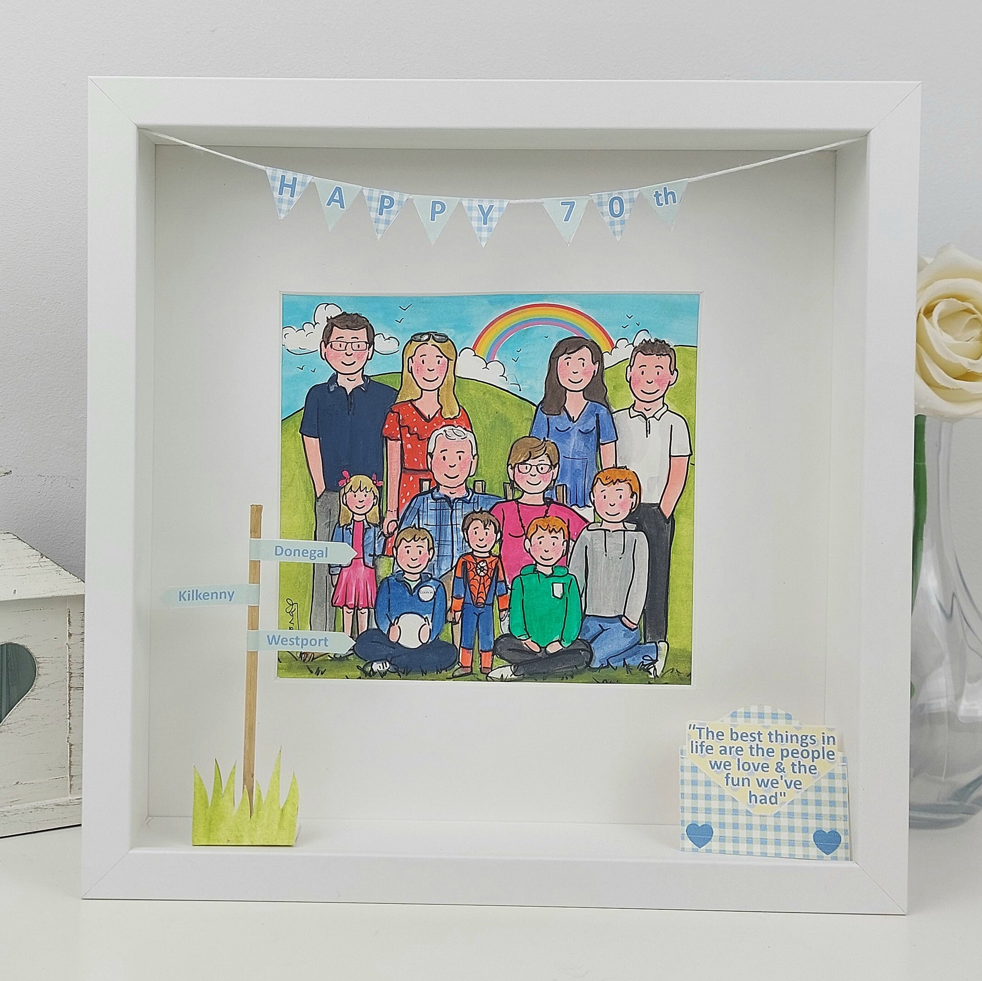 Framed illustration of a family with a rainbow and 'Happy 79th' banner, placed on a white surface.
