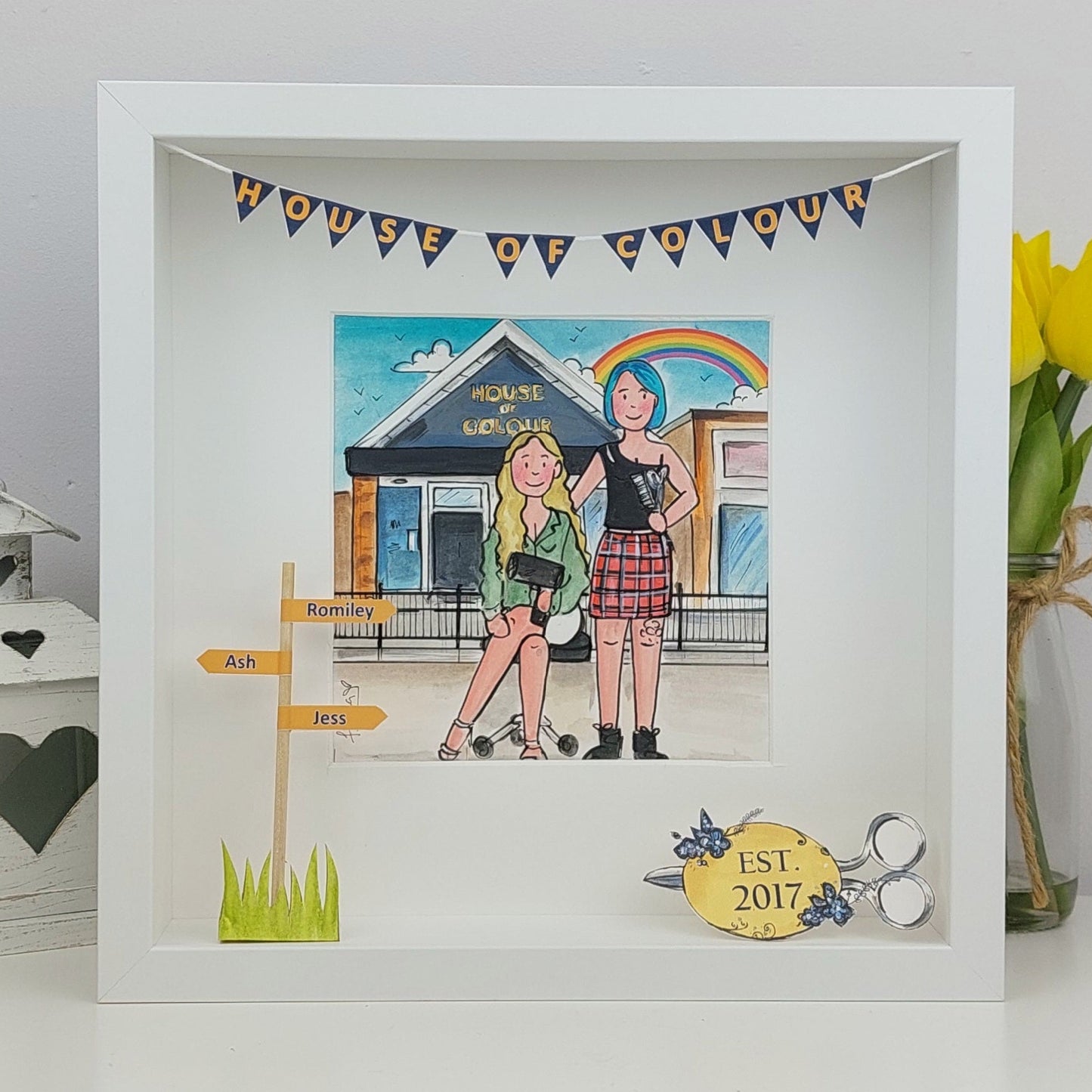 Framed artwork of two people in front of a salon with decorative elements, including a rainbow and text.