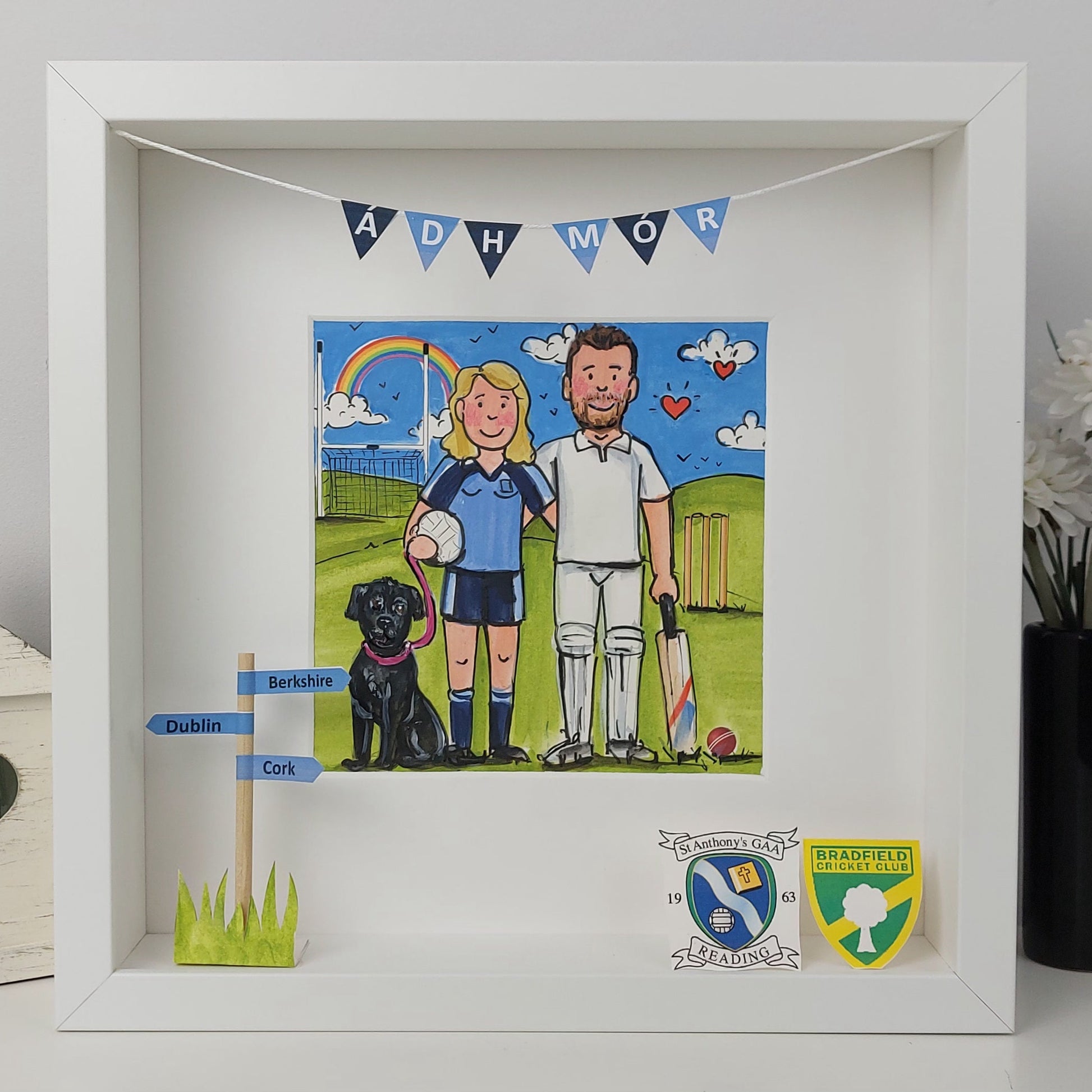 Framed artwork of a couple with a dog, cricket equipment, and decorative elements on a grassy field.