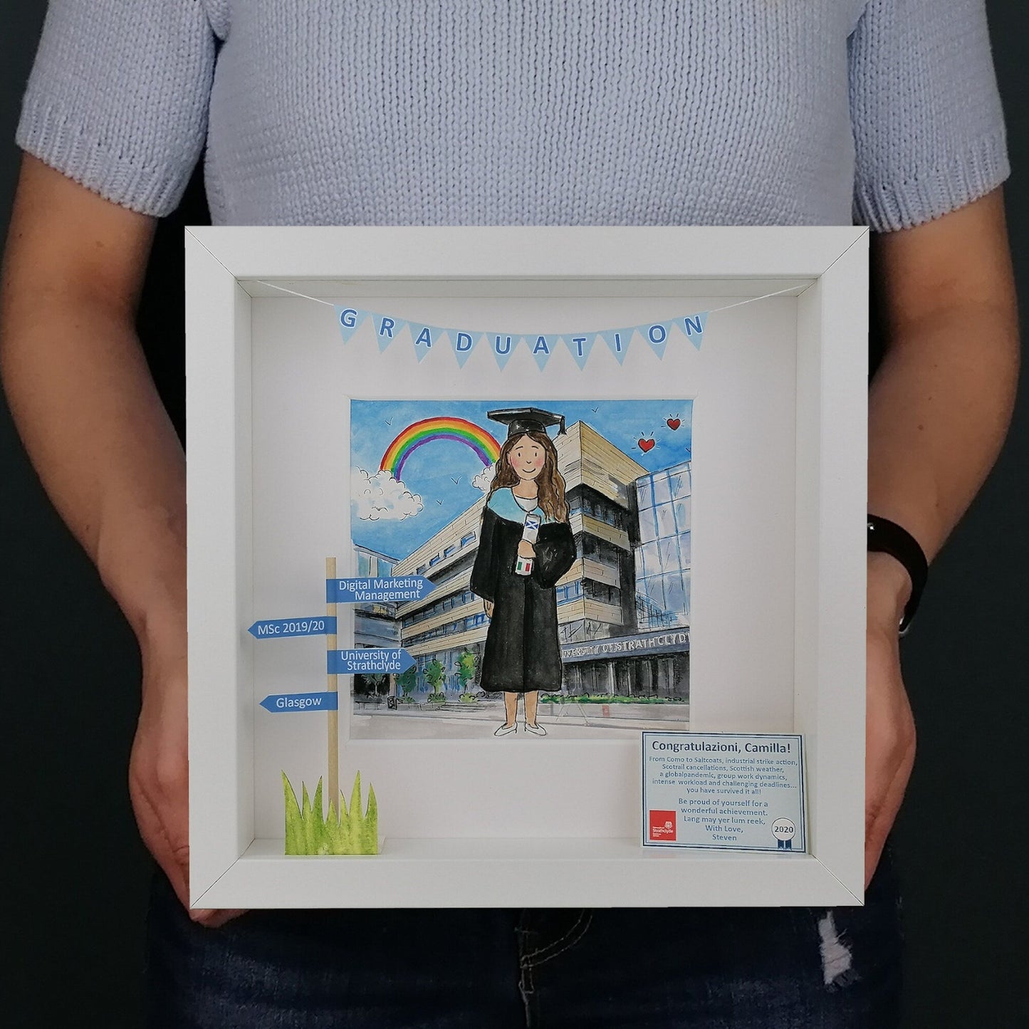 A custom illustration of a graduation girl in a blue graduation cap and gown, holding a diploma, with a white frame.