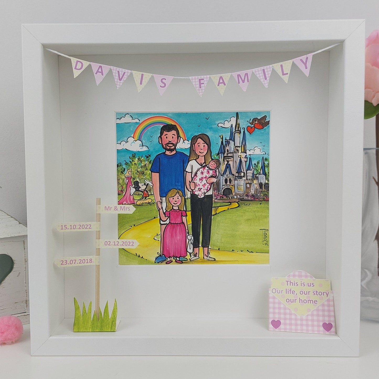A framed custom illustration of a mother with her family in Disney setting, surrounded by a colorful, decorative banner with the text 'DAVID'S FAMILY'.